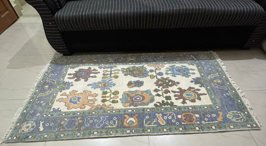 Handmade Oushak Rug with Distressed Floral Motif and Soft Blue Accents